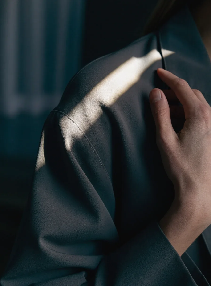 Close crop of a hand adjusting the shoulder line of a relaxed structured jacket